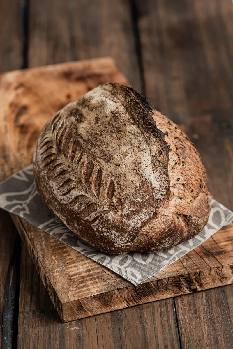 A flour-dusted country sourdough loaf on a wooden board